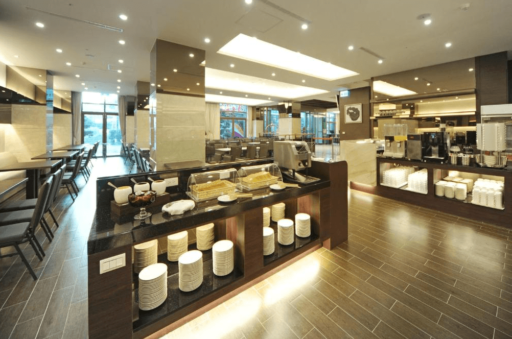 F Hotel 花蓮站前館的自助餐廳區域,空間設計現代且採光充足,取餐檯上擺放整齊的餐盤與各式飲品設備,提供旅客舒適的用餐環境。
