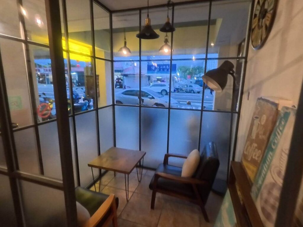 "精選示意圖"小旅行迷你公寓室內一角，設有帶玻璃隔窗的小櫥窗休閒空間，擺放著木質小方桌與黑色皮革扶手椅，上方懸掛著工業風黑色吊燈，營造出寧靜舒適的閱讀或休憩氛圍。