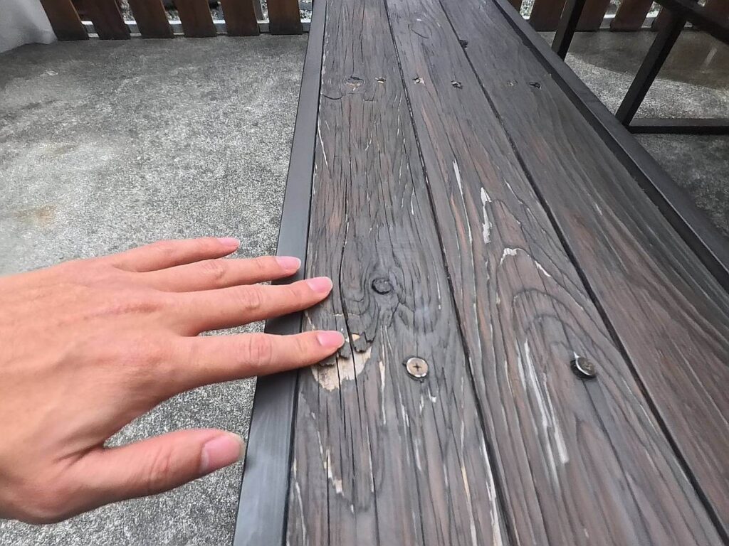 小旅行迷你公寓戶外長凳的木紋細節特寫，展現出自然的木頭質感與金屬邊框結構，整體呈現樸實的工業設計風格。