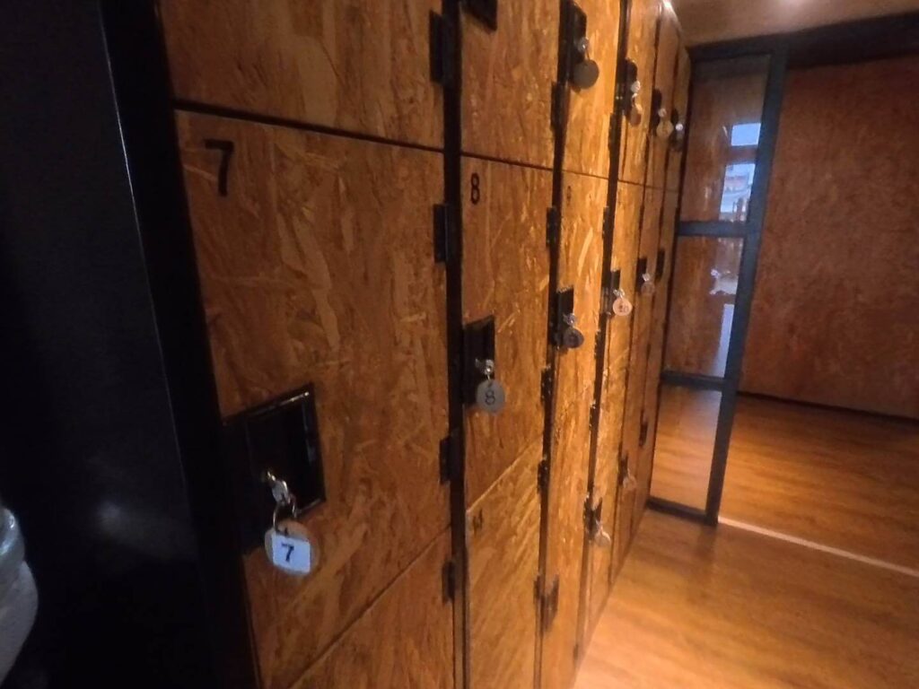 「小旅行迷你公寓（Mini Voyage Hostel）室內走廊與木質行李寄放櫃，櫃門標示著數字 7 與 8，並附有鑰匙吊牌。」