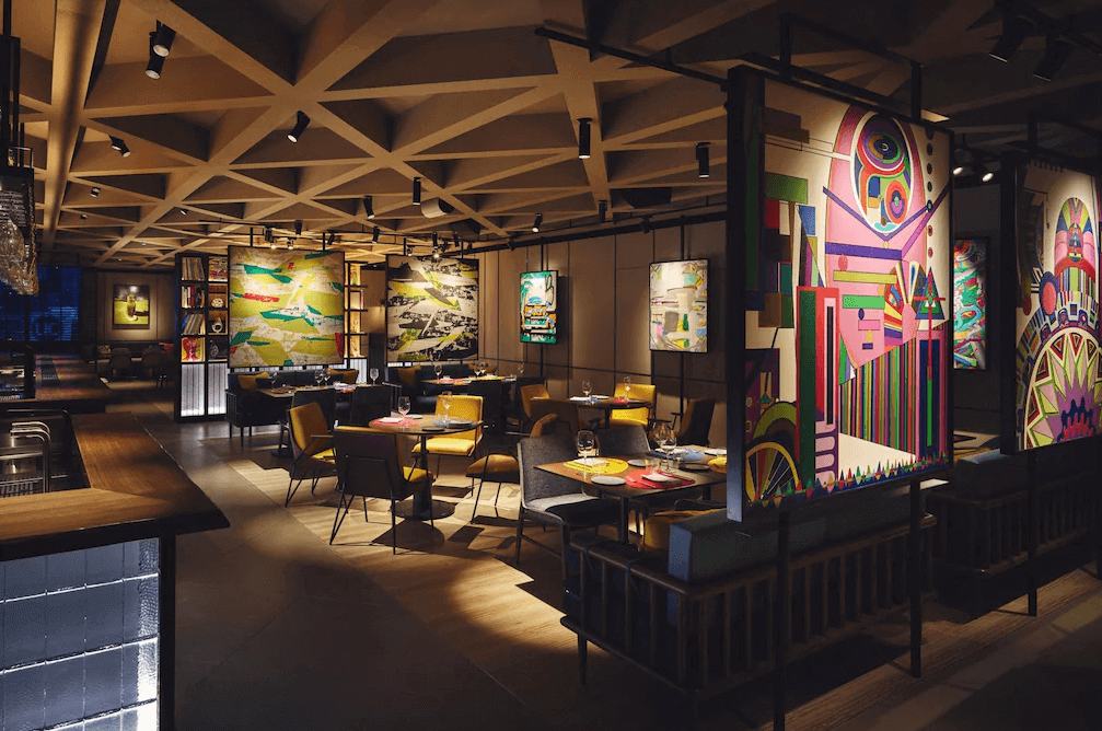 東京澀谷英迪格酒店 Gallery 11 餐廳，空間充滿大膽的色彩與幾何線條，牆面掛滿巨幅普普風藝術畫作，天花板採用交錯的格柵設計，展現澀谷獨有的潮流活力與藝術氣息。