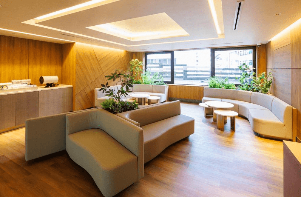 澀谷梅茲JR東酒店公共休息大廳，採用大量溫潤木質裝潢與流線型沙發設計，搭配翠綠植栽點綴，營造出如森林般的自然療癒氛圍，提供住客舒適的交誼與休憩空間。