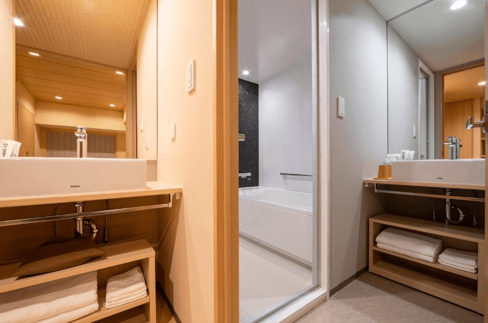 唐草飯店東京站的乾濕分離衛浴空間，外側設有寬敞的木質洗手台與大面梳妝鏡，下方提供充足的毛巾收納空間；內側則為配備獨立深型浴缸的現代化浴室，環境潔淨明亮。