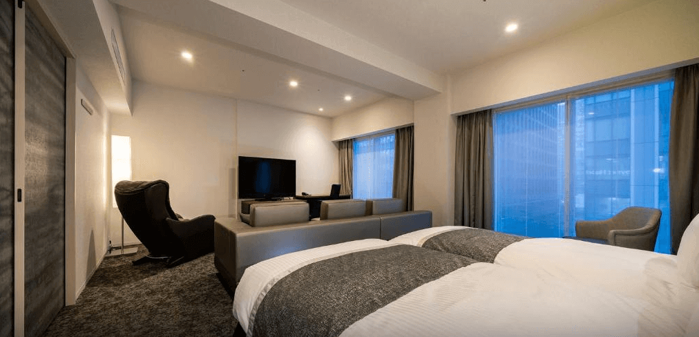 東京京橋大及魯內普米爾飯店尊榮客房，寬敞的空間內特別規劃了舒適的沙發客廳區與頂級紓壓按摩椅，大面落地窗可飽覽東京都會城市景致，提供極致放鬆的住宿體驗。