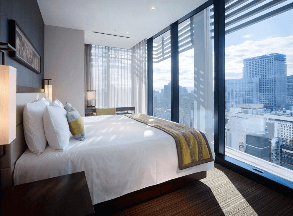 東京奧克伍德尊貴酒店豪華高樓層客房，配備舒適的特大雙人床與商務辦公桌，大面落地窗將溫暖的陽光引入室內，讓旅客能無死角俯瞰東京繁華的迷人市景與天際線。