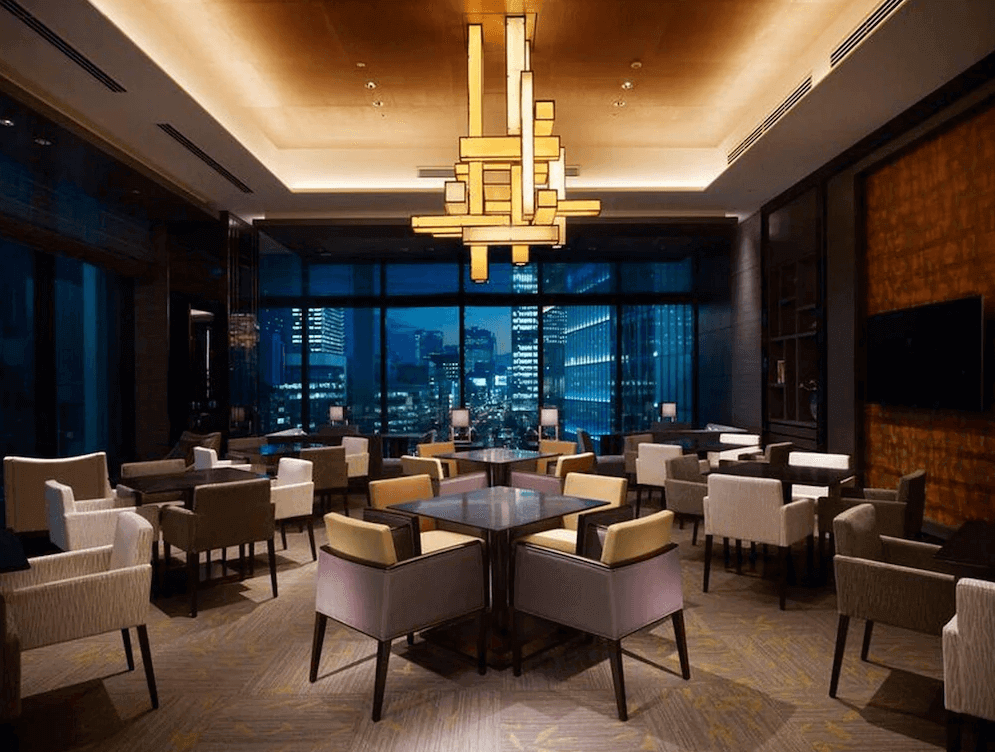 "東京車站精選示意圖"東京奧克伍德尊貴酒店高空景觀交誼客廳，室內懸掛著充滿現代設計感的幾何藝術吊燈，搭配高雅的休憩座椅，大面落地窗外展現著璀璨絢麗的東京百萬夜景，氛圍極致奢華浪漫。
