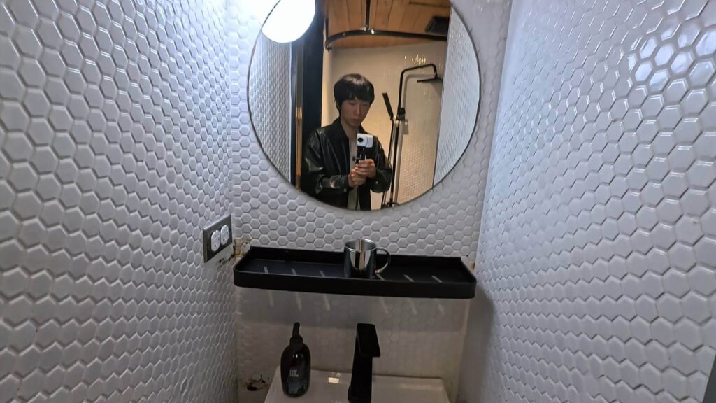 正旅館信義浴室鏡子及洗手台，圓形鏡子看起來很時尚，小小的洗手台很乾淨