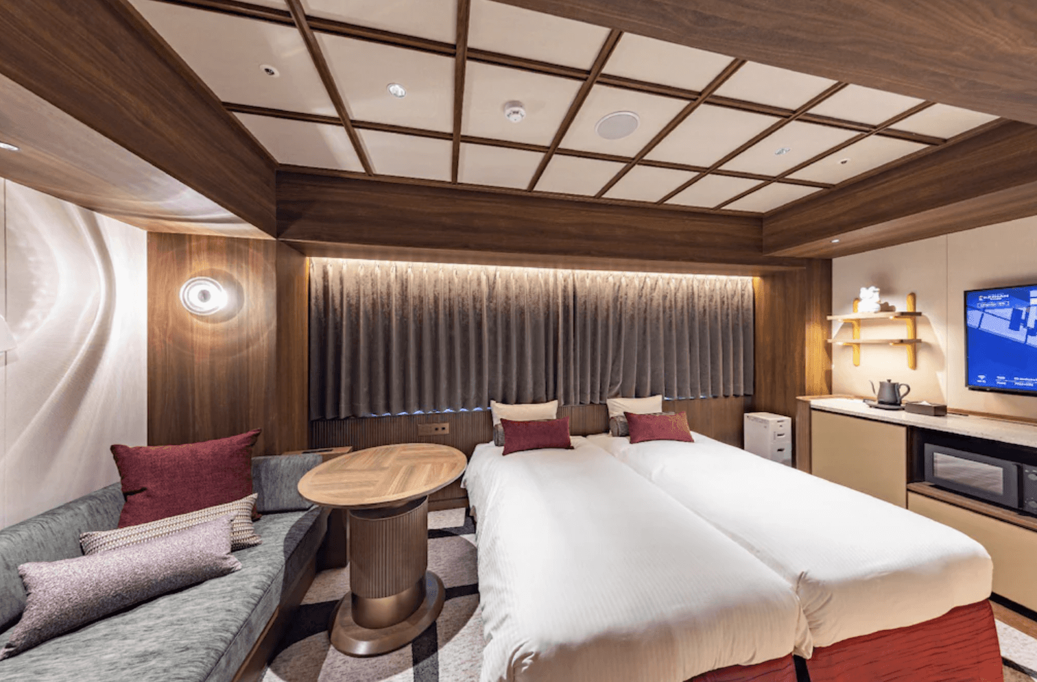 淺草京阪飯店 (Hotel Keihan Asakusa) 的精緻雙床房實景，室內採用大量木質元素與格狀天花板設計，配有兩張單人床、長型沙發與質感圓桌，營造出和洋折衷的溫馨氛圍