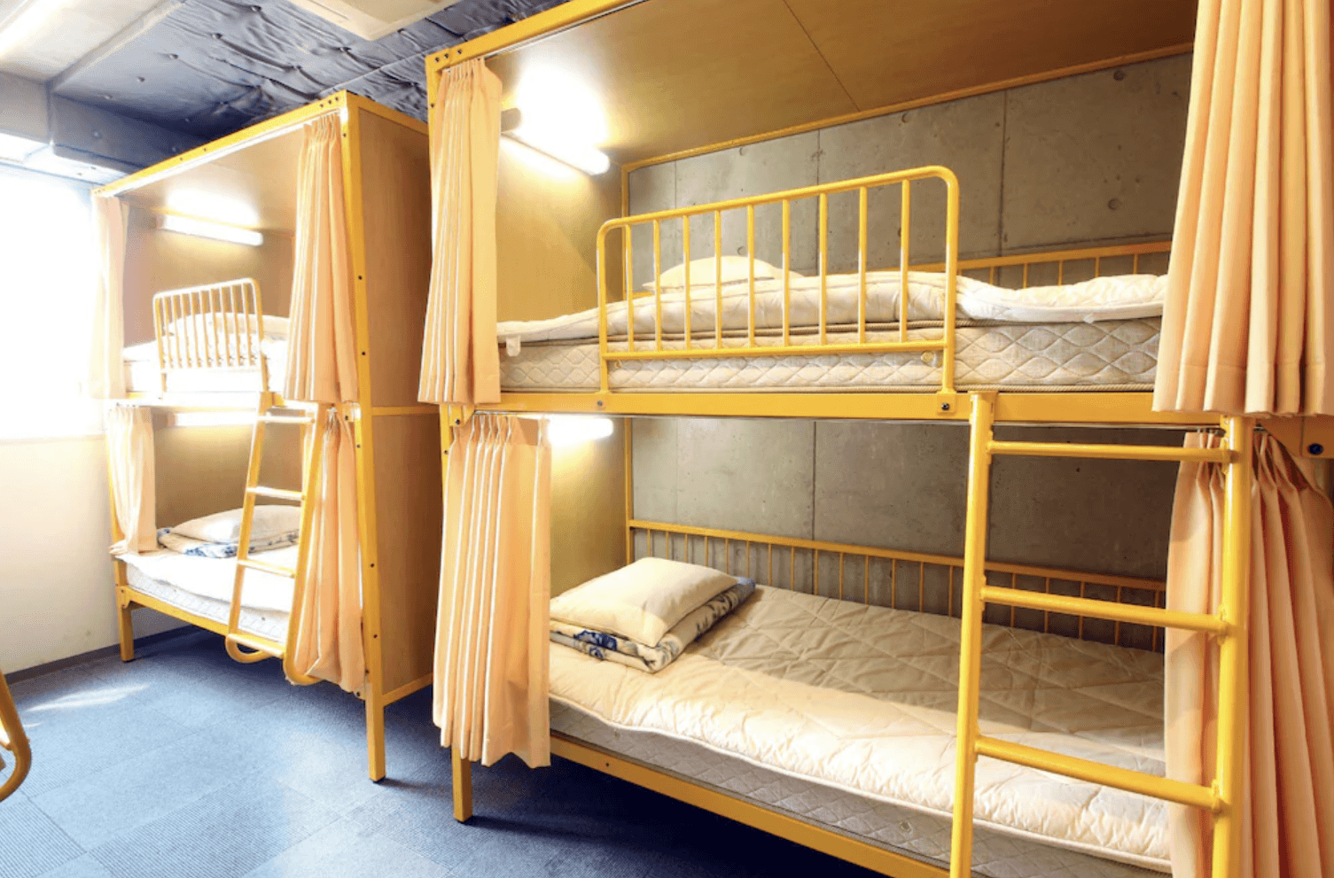 淺草櫻花青年旅館的宿舍房型實景，採用鮮黃色金屬框架的上下舖設計，每張床位皆配備遮光簾以確保住客的個人隱私