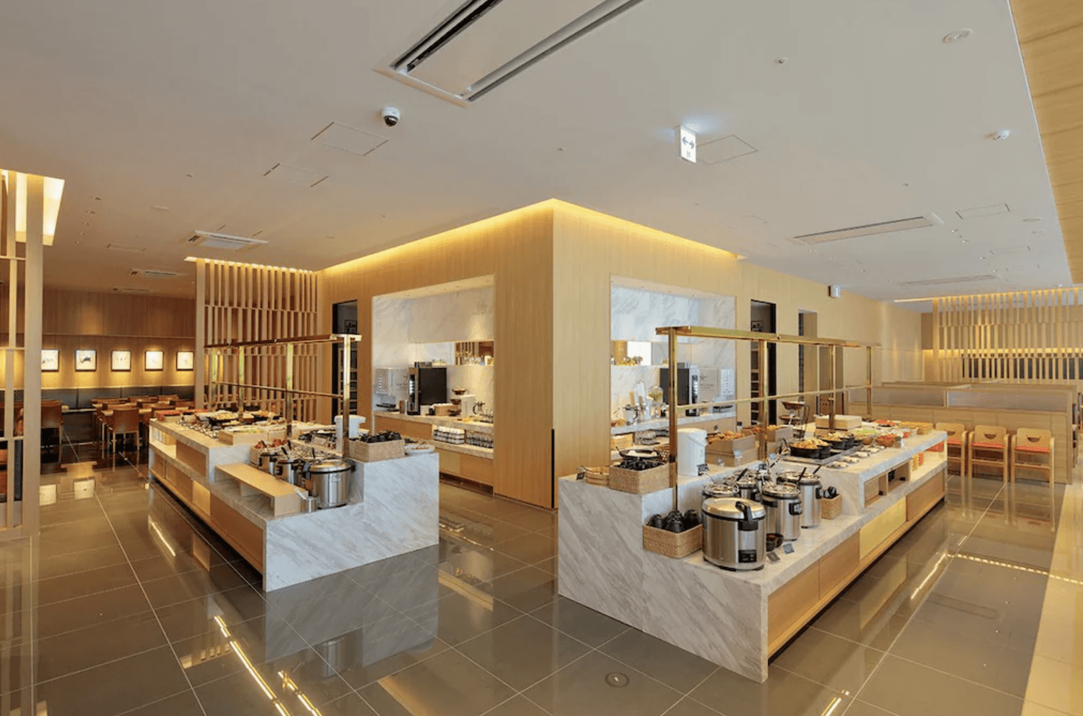 日本環球影城新格拉利飯店及空中水療中心 (The Singulari Hotel & Sky Spa at Universal Studios Japan) 的現代化自助餐廳,空間明亮且採用大量木質元素裝潢,中央的大理石取餐檯上整齊陳列著各式餐點、保溫餐爐與烹煮設備,用餐環境溫馨舒適