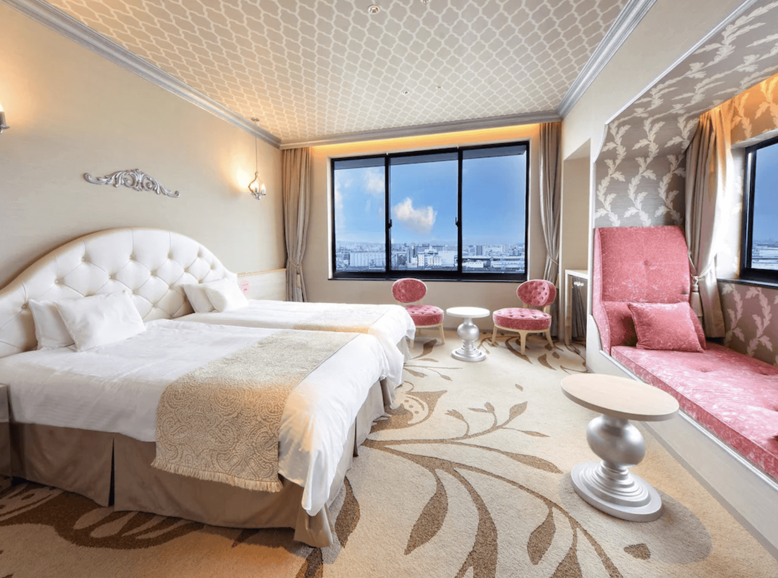 環球影城維塔港酒店 (Hotel Universal Port Vita)的典雅客房,設有白色軟墊床頭板的床位、大面景觀窗戶,以及粉紅色的窗邊沙發休息區與座椅