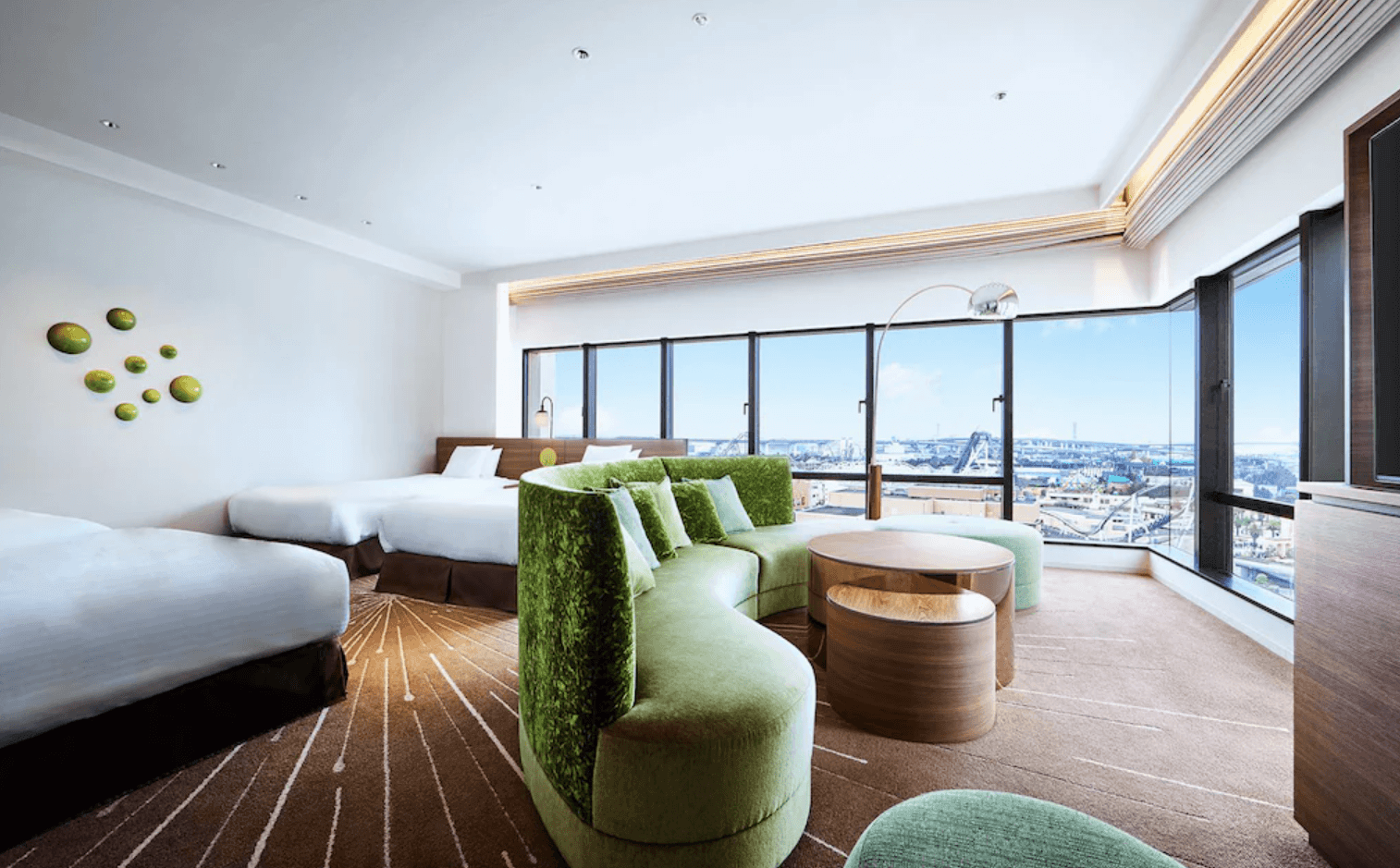 環球影城維塔港酒店 (Hotel Universal Port Vita)的寬敞三人客房,房內中央設有一組搶眼的綠色弧形沙發,並配有大面積轉角窗戶可飽覽城市與周邊景色