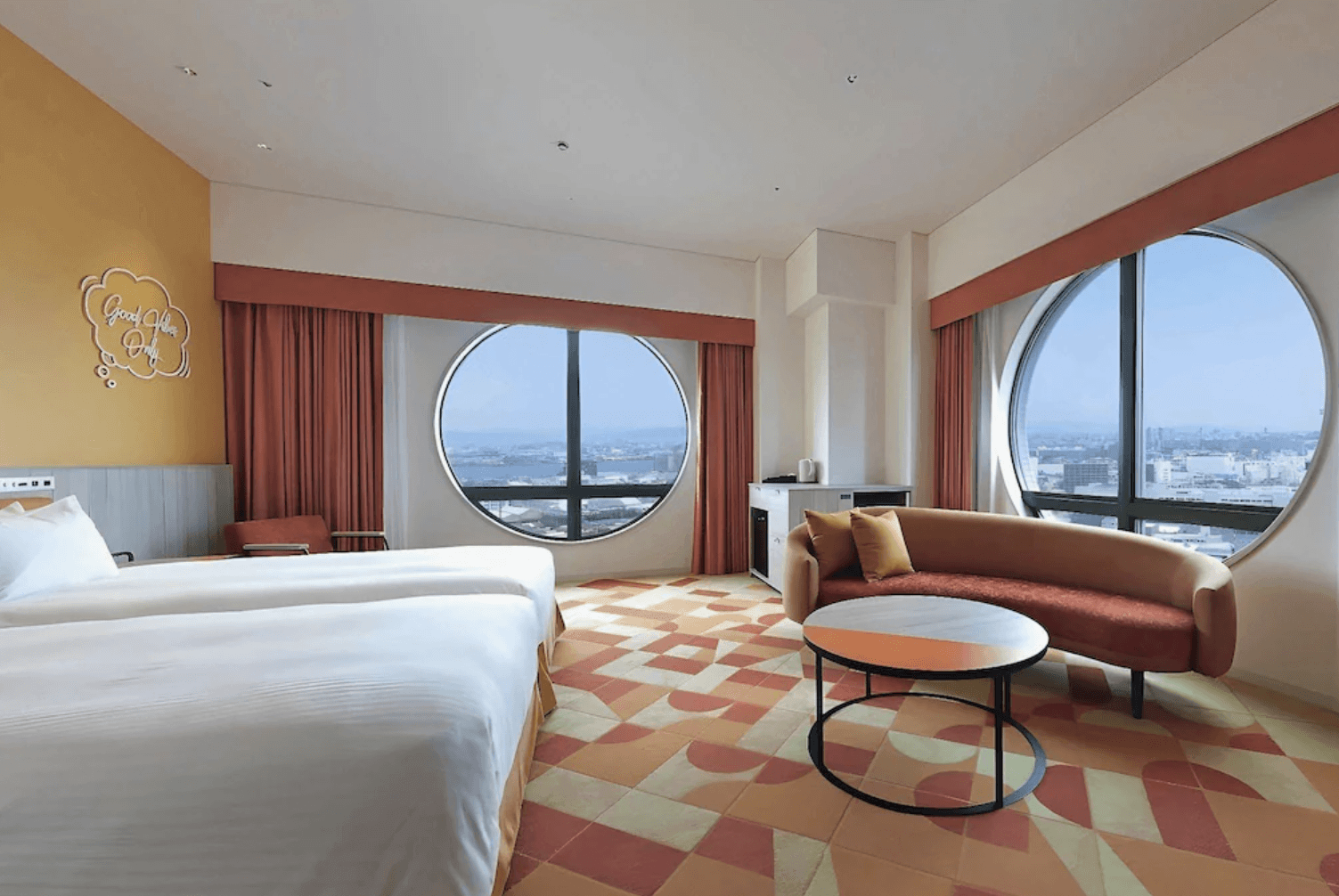 近鐵環球城飯店 (Hotel Kintetsu Universal City) 的特色客房,空間以亮眼的橘黃色調搭配幾何圖紋地毯。房內設有兩張單人床、一張橘色弧形沙發與圓形茶几,最吸睛的是兩面能飽覽城市與港灣景緻的大型圓形景觀窗戶