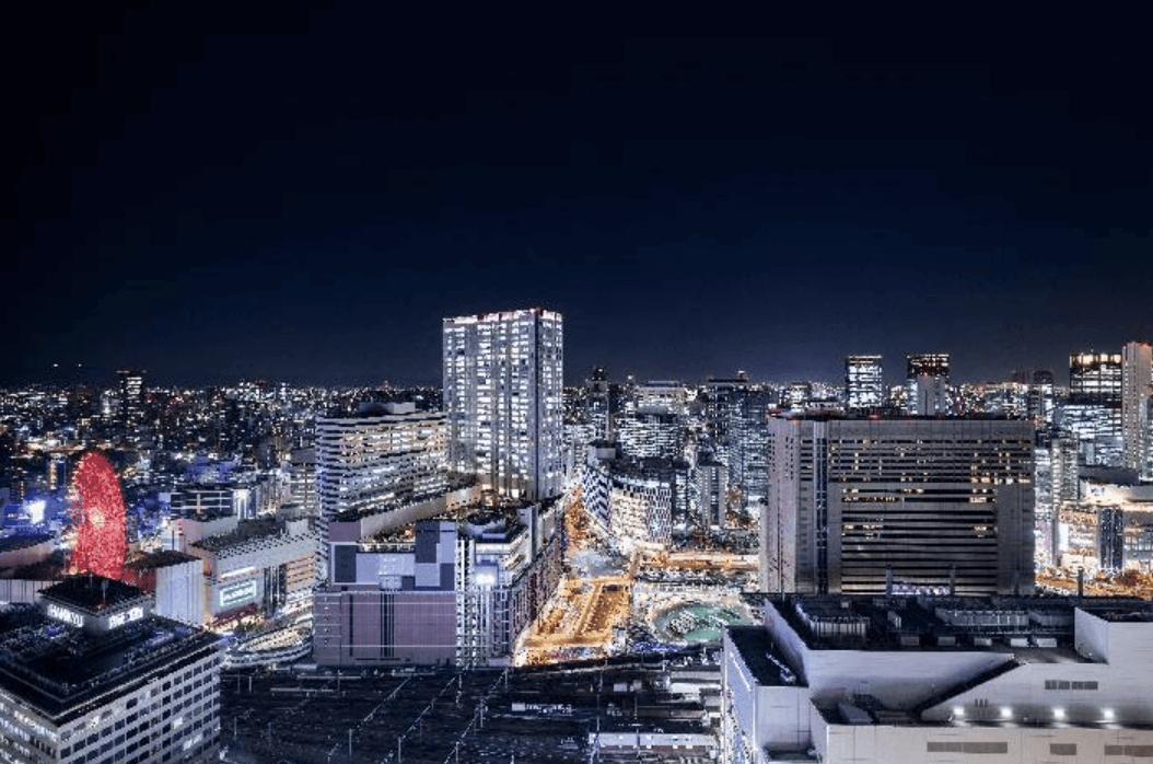 從高處俯瞰的夜晚大阪城市景觀航拍照片，無數城市燈光將夜空點亮。畫面中心是包括阪急大阪龍仕柏飯店在內的高樓大廈，左側遠處可以看到 Hep Five 摩天輪發出紅光